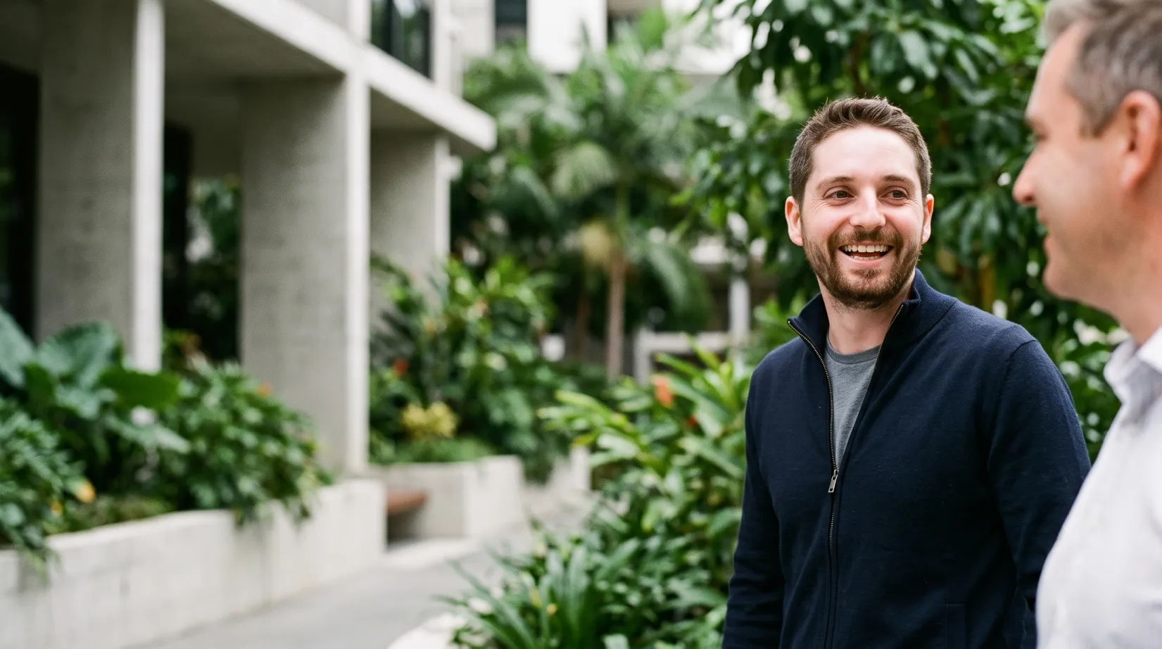 Jonathon De Martini, Middle Park financial planner, and a client walking and smiling together during a professional outdoor consultation in Brisbane.